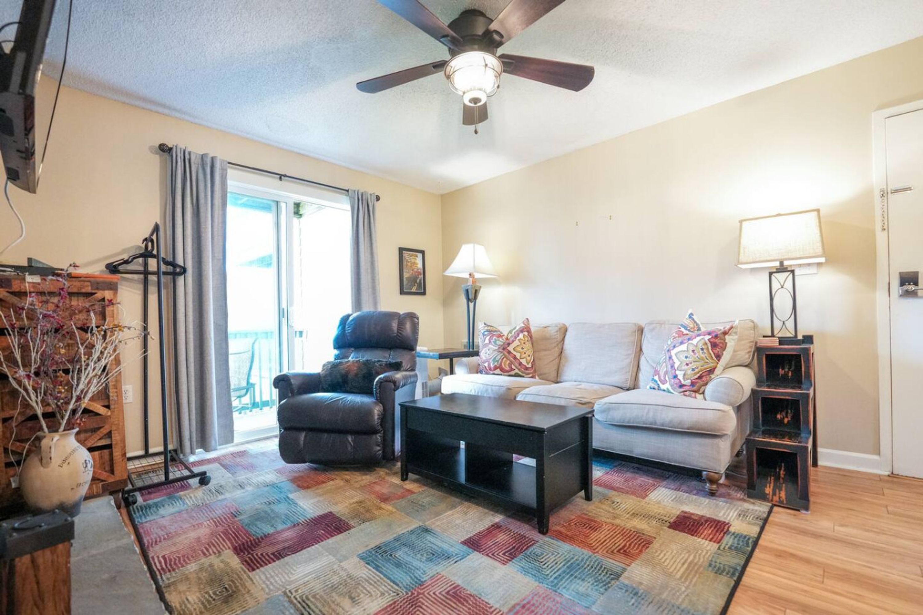 A living room with a ceiling fan, a sofa, a chair, a coffee table, and a patterned rug.