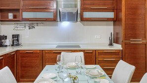 Una cocina moderna con armarios de madera, estufa integrada y una mesa de comedor para cuatro personas.