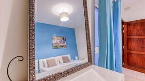 Un dormitorio con un espejo grande, una cama, un cuadro en la pared y un armario de madera.
