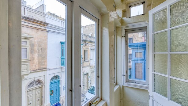 Una habitación con amplios ventanales que dan a una calle con edificios tradicionales.