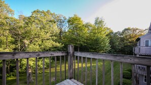A wooden deck with a railing overlooking a grassy area with trees and a building in the background. - Top 3rd Floor Loft Resort Access No Elevator (Claysburg)