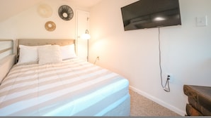 A bedroom with a bed, a TV mounted on the wall, and a bedside table. - Top 3rd Floor Loft Resort Access No Elevator (Claysburg)