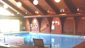An indoor swimming pool with wooden beams and a chair by the pool. - Shanty Creek 2bd 2ba Adjoining Rooms Ski-golf (Mancelona)
