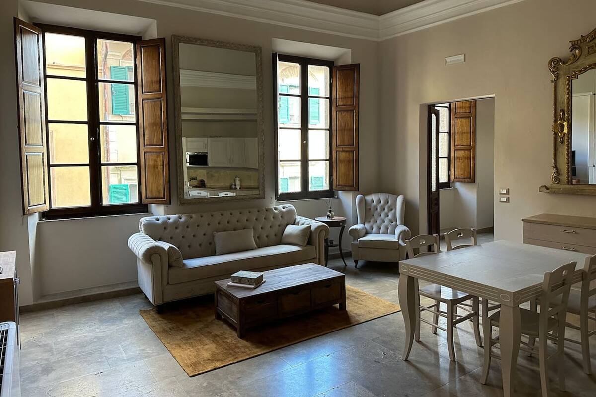 Una sala de estar con sofá, sillones, una mesa de centro y una mesa de comedor.