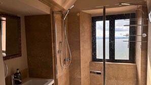 A bathroom with a shower, a sink, and a window with a view of the sea. - Tuscan Palace - Venturi Apartment (Montepulciano)