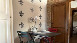 A dining area with a table and chairs, a potted plant, and decorative wall patterns. - Tuscan Palace - Petit Apartment (Montepulciano)