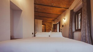 A bedroom with a large bed, a wooden ceiling, and a window with curtains. - Tuscan Palace - Petit Apartment (Montepulciano)
