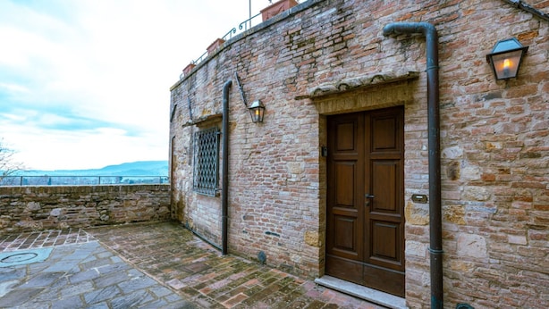 A stone building with a wooden door and a metal gate. - Tuscan Palace - Petit Apartment (Montepulciano)