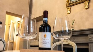Une bouteille de vin et deux verres sur une table, accompagnés d’une carte de remerciement.