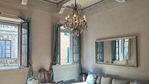 Une pièce avec un lustre, un grand miroir, un canapé et une table.