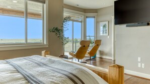 A bedroom with a large bed, a TV mounted on the wall, and a view of the outdoors through a sliding door. - Oceanfront Comfort Style Luxury Hot Tub Wifi 600 35 (Long Beach)