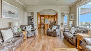 A spacious living room with leather sofas, wooden flooring, and a view of the kitchen and dining area. - Oceanfront Comfort Style Luxury Hot Tub Wifi 600 35 (Long Beach)