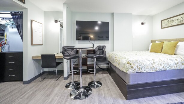 A modern hotel room with a bed, a desk, two chairs, a TV, and a wardrobe. - Workspace Studio Ski-in Ski-out AC (Snowshoe)