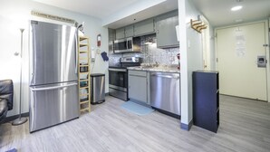 A compact kitchen with stainless steel appliances, a wooden ladder, and a built-in microwave. - Workspace Studio Ski-in Ski-out AC (Snowshoe)