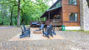 A log cabin with a deck, outdoor seating, and a fire pit.
