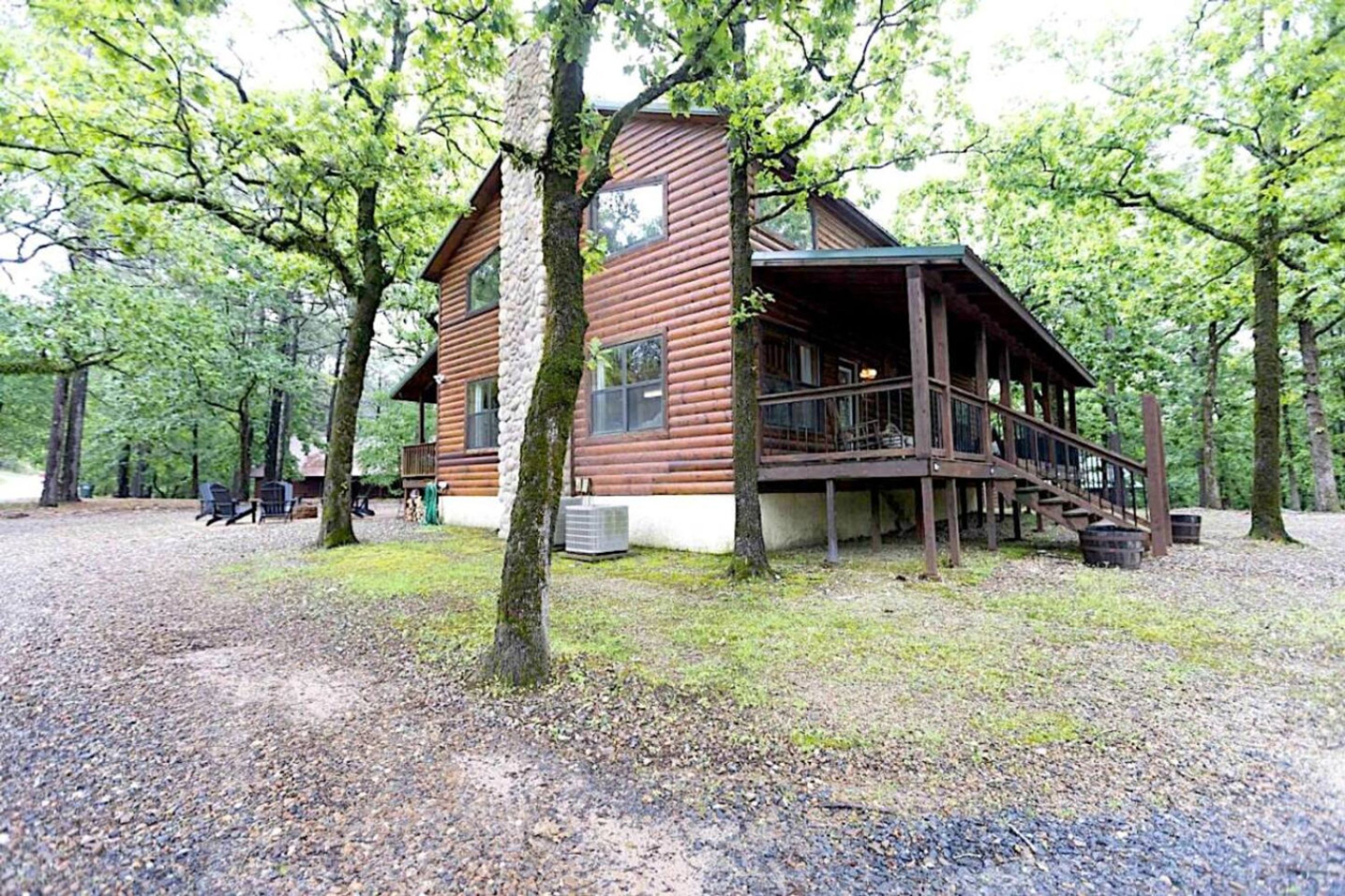 Une cabane en rondins avec un porche et une allée gravillonnée.