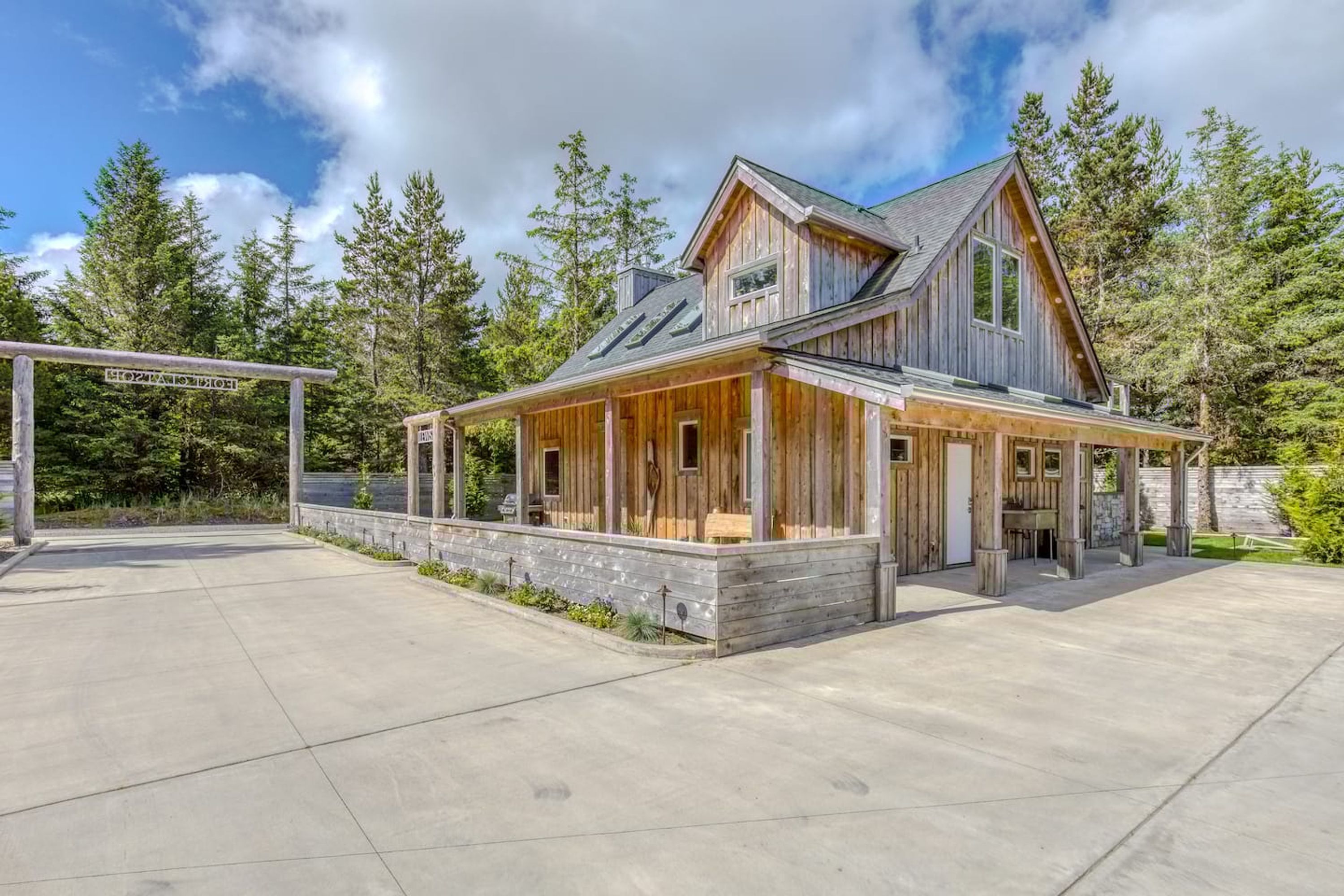 A two-story wooden house with a covered porch and a stone wall.