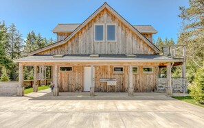 A wooden cabin with a gabled roof, a covered porch, and a stone foundation. - Boutique Cabin Design Luxury Hot Tub Path to Beach (Long Beach)