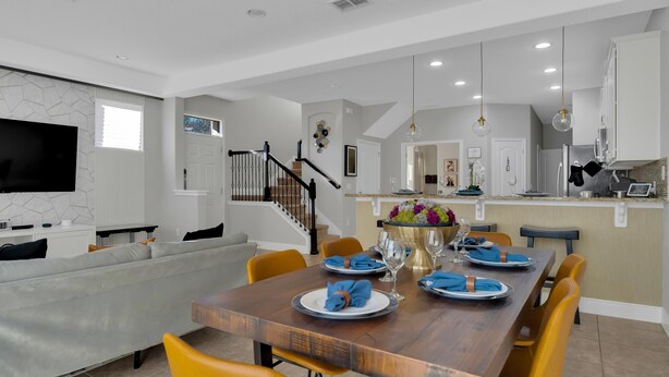 A modern dining area with a wooden table set for four, surrounded by yellow chairs. - Come and Stay at the Best of Championsgate! (Davenport)