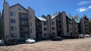 A multi-story residential building with a modern design, featuring balconies and a parking area with several cars. - Ski-in Ski-out Chair 8 3rd Floor No Elevator (Brian Head)