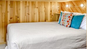 A bedroom with a wooden wall, a bed with a white bedspread, and colorful pillows. - Ski-in Ski-out Chair 8 3rd Floor No Elevator (Brian Head)