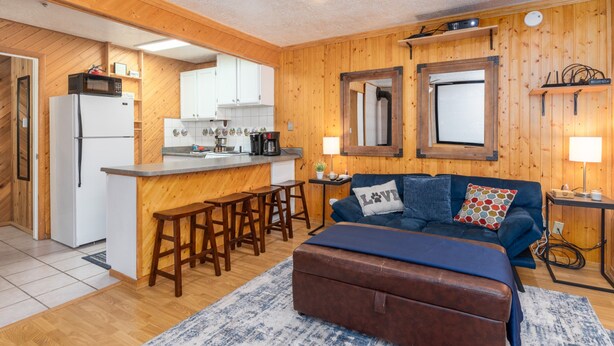 A cozy cabin-style room with a kitchenette, a sofa with a 'Love' pillow, and a wooden ceiling. - Ski-in Ski-out Chair 8 3rd Floor No Elevator (Brian Head)