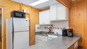 A compact kitchen with white cabinets, a microwave, a refrigerator, a stove, and a coffee maker. - Ski-in Ski-out Chair 8 3rd Floor No Elevator (Brian Head)