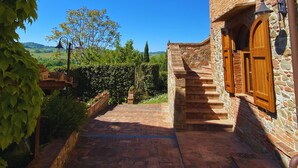A stone building with a wooden staircase leading to a door, surrounded by greenery and a clear blue sky. - Agriturismo Borgo Sette Tigli Apt 3 (Montepulciano)
