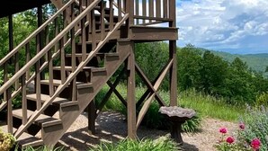 A wooden staircase leading to a deck with a birdbath and flowers. - Blue Ridge Gateway Cabin With Mountain Views (Moravian Falls)