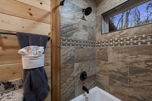Un baño moderno con ducha, bañera y ventana.