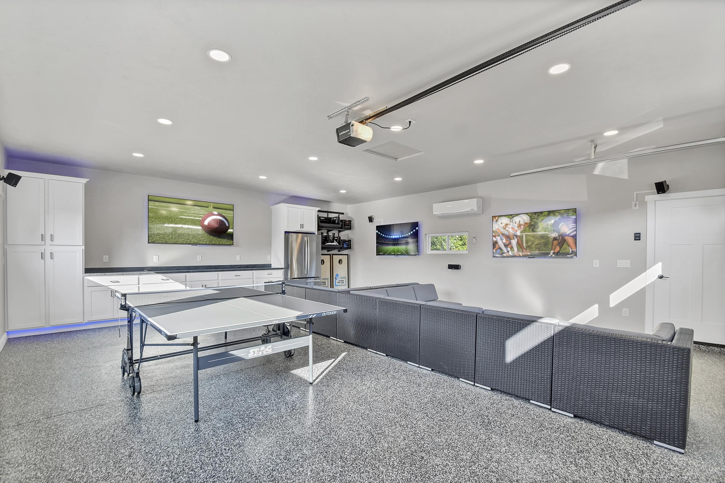 A modern indoor space with a ping pong table, white cabinets, and artwork on the walls.