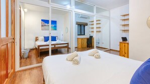 Ein Hotelzimmer mit einem großen Bett, einem Schreibtisch und Blick durch eine Glastür.