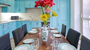 Ein Esszimmer mit einem Holztisch, gedeckten Plätzen für sechs Personen, blauen Schränken und einer Vase mit Blumen.
