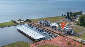 An aerial view of a coastal hotel with a marina, buildings, and a large parking area. - Ground Floor Waterfront on The Rez in Madison (Madison)