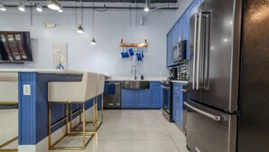 A modern kitchen with blue cabinets, stainless steel appliances, and pendant lighting. - Ground Floor Waterfront on The Rez in Madison (Madison)