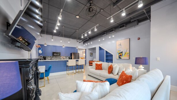 A modern living room with a white sofa, a coffee table, and a kitchen area in the background. - Ground Floor Waterfront on The Rez in Madison (Madison)