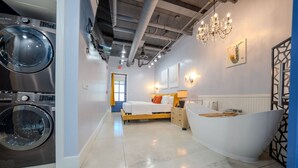 A modern hotel room with a large bed, a bathtub, and a washing machine. - Ground Floor Waterfront on The Rez in Madison (Madison)