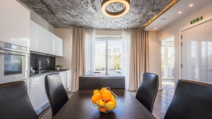 A modern dining area with a table set for four, a bowl of oranges, and a view of the kitchen and dining area. - Balanzone s Creative Penthouse (Msida)