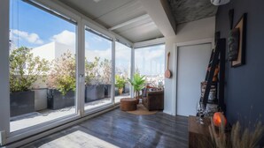 A modern living room with large sliding glass doors, a wooden floor, a brown sofa, a coffee table, and a guitar on the wall. - Balanzone s Creative Penthouse (Msida)