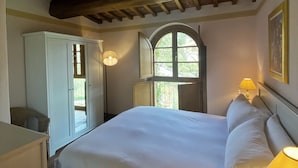 A bedroom with a large bed, a wardrobe, a window with a view, and a lamp. - Agriturismo Borgo Sette Tigli Apt 5 (Montepulciano)
