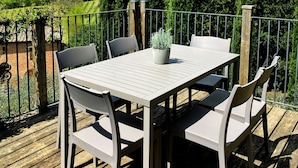 A wooden deck with a table and chairs, surrounded by a metal railing and tall trees. - Agriturismo Borgo Sette Tigli Apt 5 (Montepulciano)