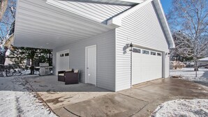 Un garage fermé avec un sol en béton, une façade blanche et une porte dotée d’une fenêtre.