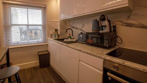 Una cocina moderna con gabinetes blancos, encimera de mármol y estufa empotrada.