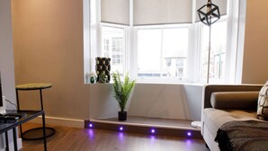 A modern living room with a large window, a round rug, a sofa, and a small table. - Luxury Charming Seaside Flat Weymouth (Weymouth)