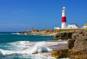 A lighthouse on a rocky coastline with waves crashing against the shore.