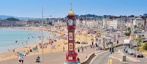 A clock tower with a clock, surrounded by a beach and buildings.