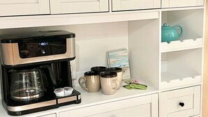 A kitchenette with a coffee maker, mugs, and a tea pot on a white cabinet. - The Old Man the Sea-seaview 101 (Madeira Beach)
