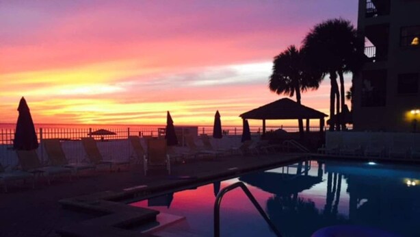 A pool area with lounge chairs and a gazebo at sunset. - The Old Man the Sea-seaview 101 (Madeira Beach)