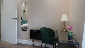 A room with a white door, a green chair, a black TV on a stand, a lamp, and a potted plant. - Casa Bella in Sherborne s Historic Quarter (Sherborne)