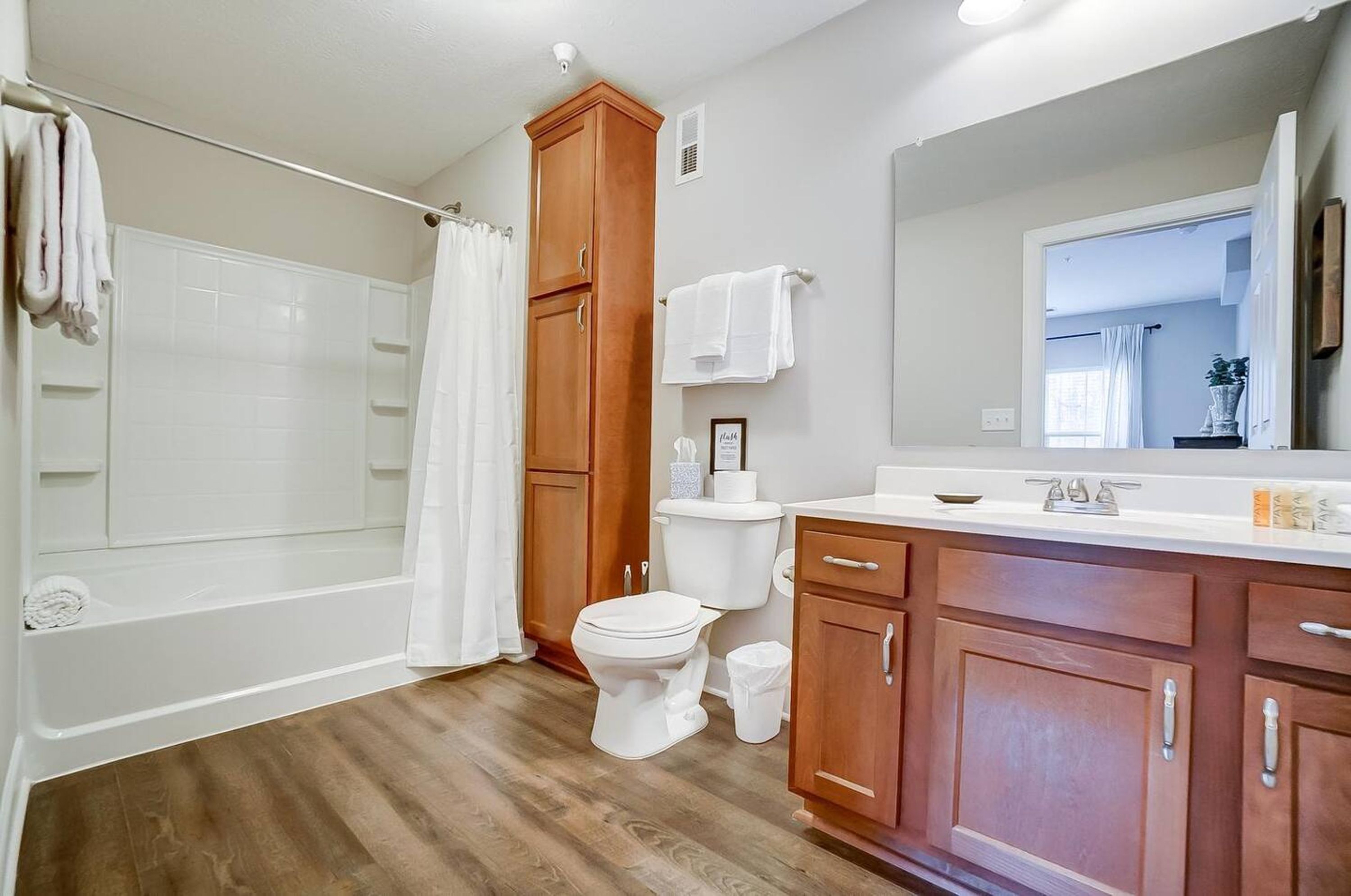 A bathroom with a bathtub, toilet, and wooden cabinets.